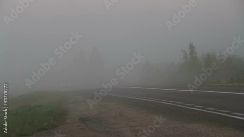 Extremal driving on the country road. Car moving into the thick fog with  rear lights and stop signal on