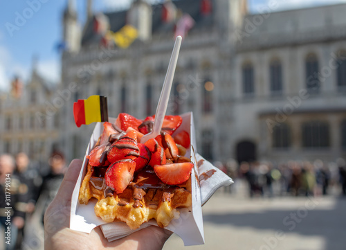 Traditional Belgian waffle dessert. Delicious cake with chocolate and fruits with flag. 