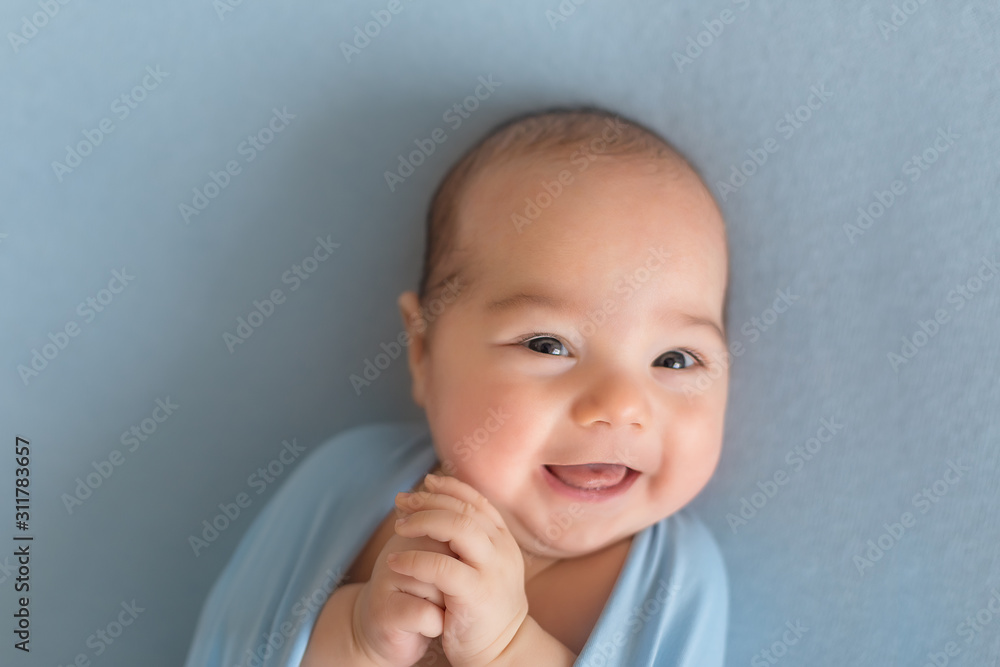 first photo session. newborn child. the child is smiling lying on a blue blanket first photo session. newborn child. the child is smiling lying on a blue blanket