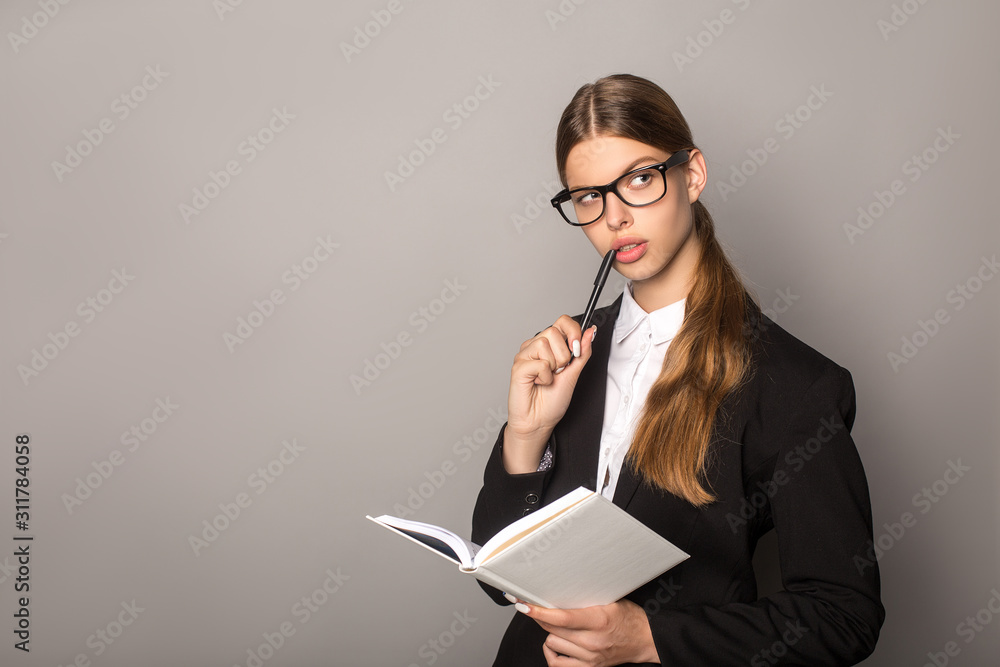 pensive businesswoman holding notebook and pen isolated on grey