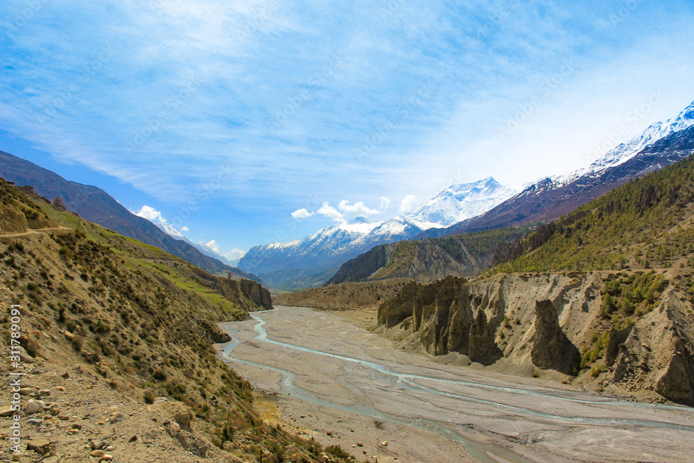 A river in the mountains of Nepal. Far snow peaks and blue sky A river in the mountains of Nepal. Far snow peaks and blue sky