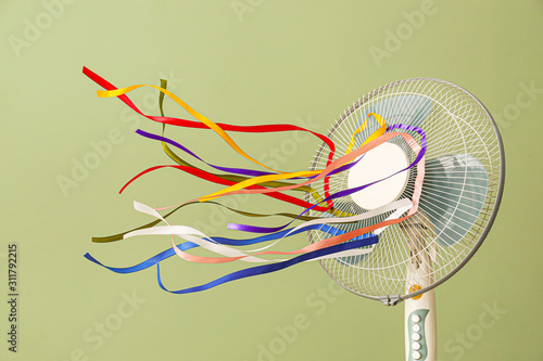 Schilderij op canvas Electric fan with fluttering ribbons on color background