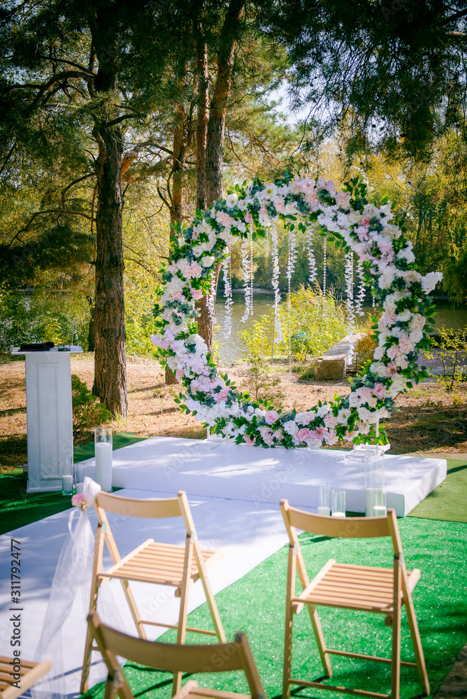 Wedding ceremony. Floral wedding decor in the park. American wedding. Chairs, arch and flowers for a wedding ceremony in a park