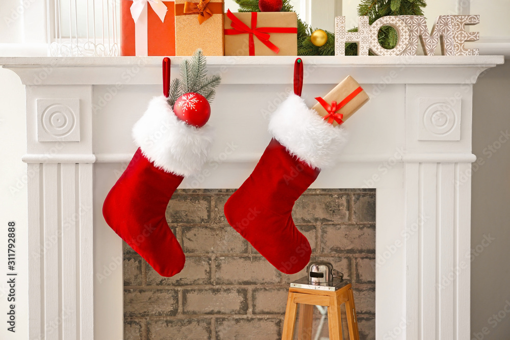 Fototapeta premium Christmas socks with gifts hanging on fireplace in room