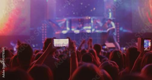 People are filming a singer’s concert on smartphone. Сrowd of people at an artist's concert, filming a performance on the phone. photo