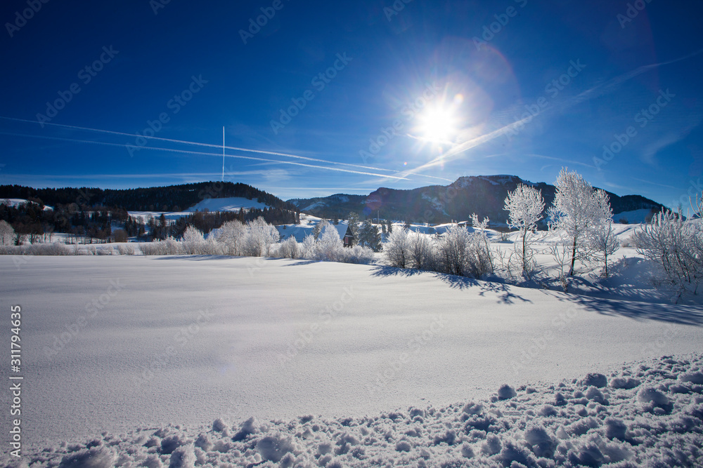 sun and blue sky on a cold day in the swiss mountains with snow landscape