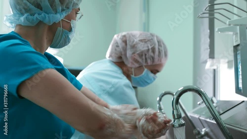 Doctors surgeon in robe washes hands in washbasin before surgery