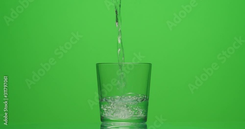 man pours a glass of water on a green background