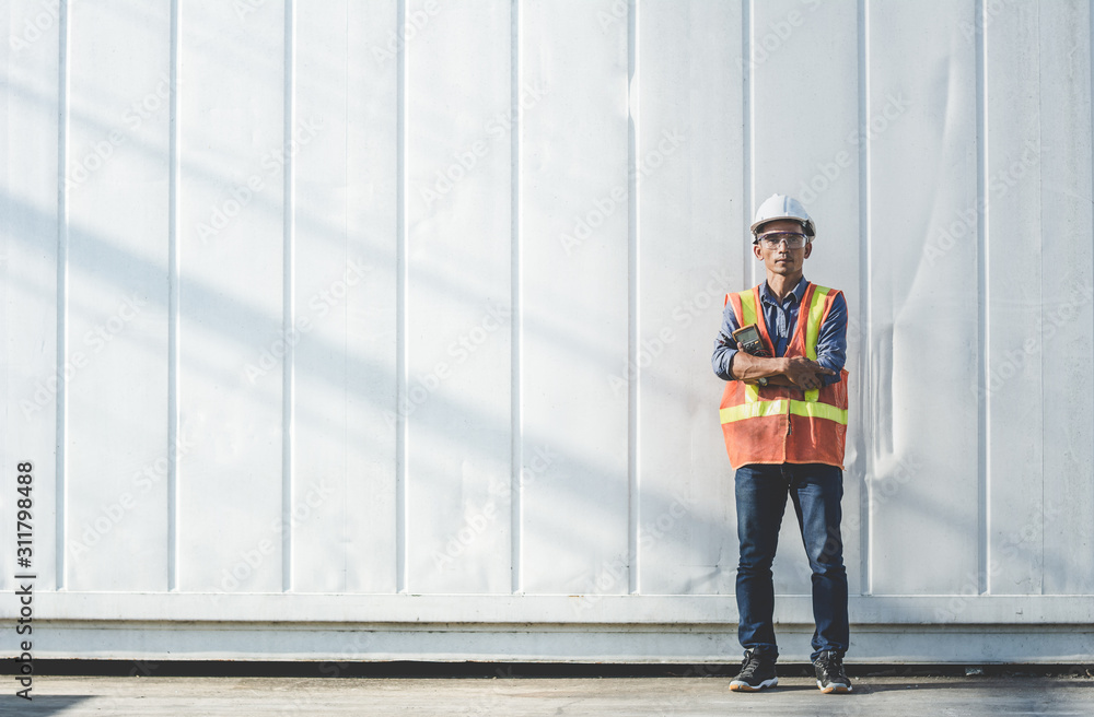 Thai handsome man engineer standing with a meter in front of the container. Thai handsome man engineer standing with a meter in front of the container.