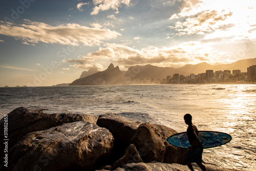 Surfer with surfboard in hand watching sunset at Pedra do Arpoador, Arpoador Beach, Rio de Janeiro, Brazil photo