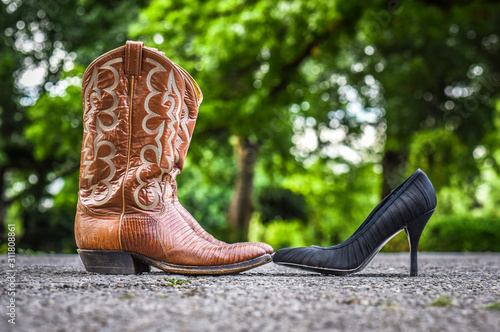 Boot and Black high heals facing earth other on the road 