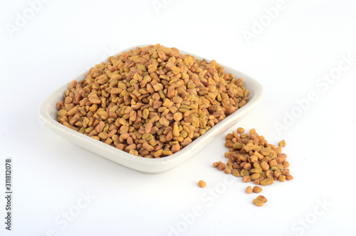 Fenugreek seeds in white plate isolated on white background photo