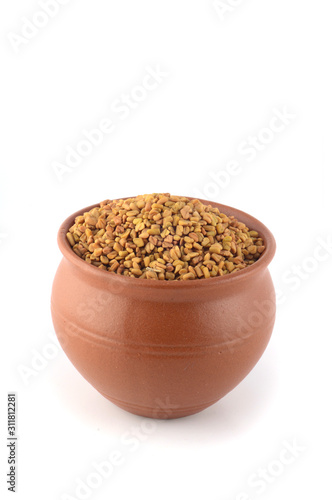 Fenugreek seeds in clay pot isolated on white background photo