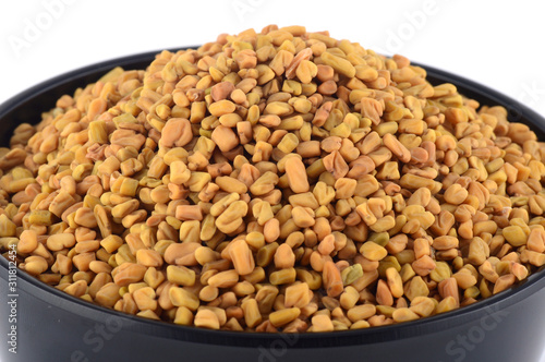 Fenugreek seeds in bowl isolated on white background photo