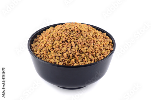 Fenugreek seeds in bowl isolated on white background photo