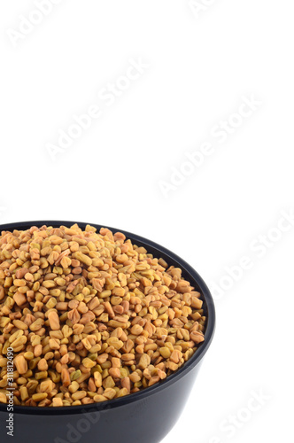 Fenugreek seeds in bowl isolated on white background photo