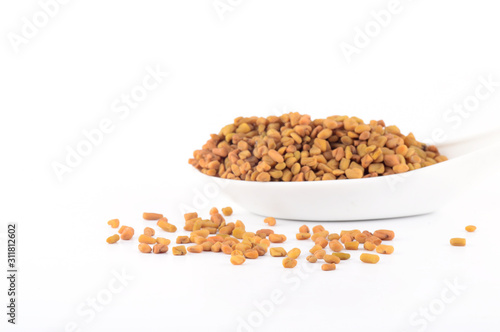 fenugreek seeds in spoon isolated on white background photo