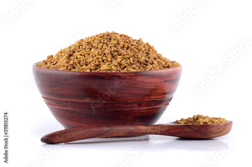 Fenugreek seeds in wooden bowl with spoon isolated on white background photo