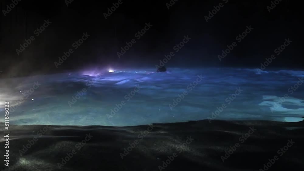slow motion of a person swimming in steaming pool by night with lights in the pool. Man swimming at night. illuminated pool. slow motion of a person swimming in steaming pool by night with lights in the pool. Man swimming at night. illuminated pool.