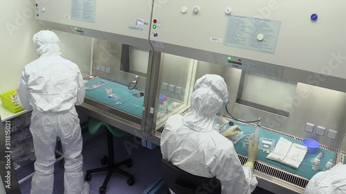 People with sterile protective clothing, mouth masks and gloves preparing medicines in a hospital pharmacy laboratory. Preparing medication for patients. photo