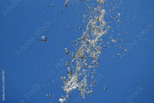 Splashes of flying water from the fountain against the blue sky