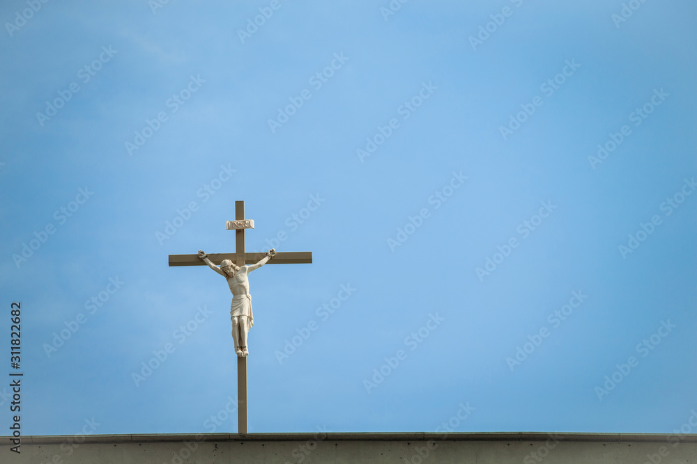 Catholic Church's Statue of jesus on cross against blue sky, top of the world.