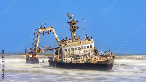Fényképezés A long exposure shot of a fishing trawler shipwrecked on the Skeleton Coast of Namibia, covered with nesting birds