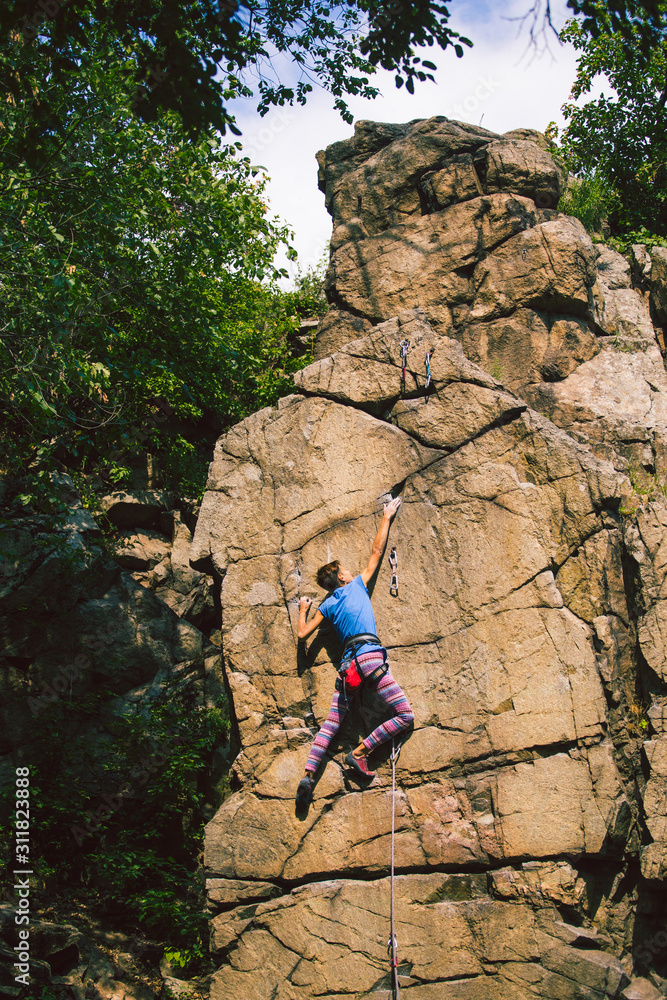 Fototapeta premium The girl climbs the granite rock.