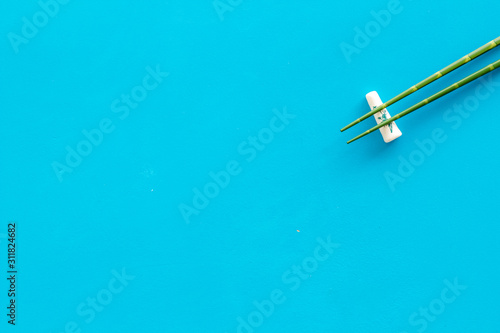 Chopsticks - green wooden utensil for sushi and rolls - on blue background top-down copy space
