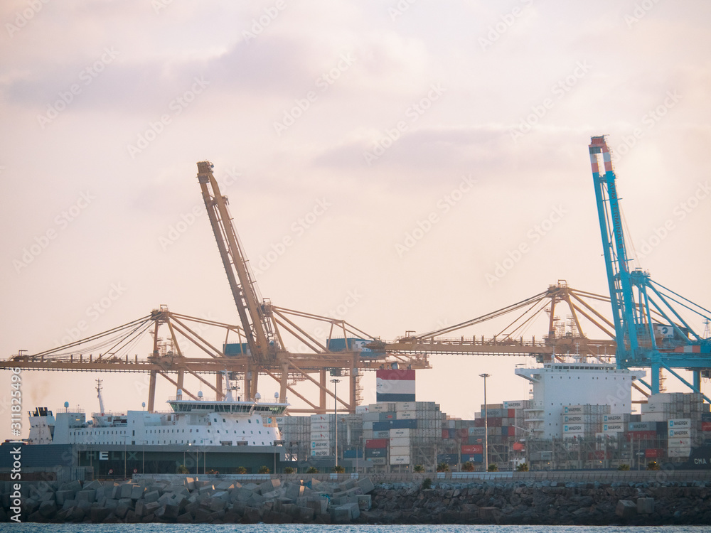 Barcelona, Spain - august 2019: industrial harbour in Barcelona, long view. Ships at wharf. Big cargo cranes loading bulks on ships. Mediterranean sea. Selective soft focus. Blurred background