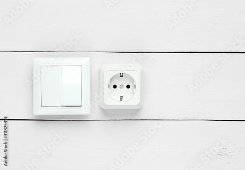 Power socket and switch on white wooden wall, minimalism