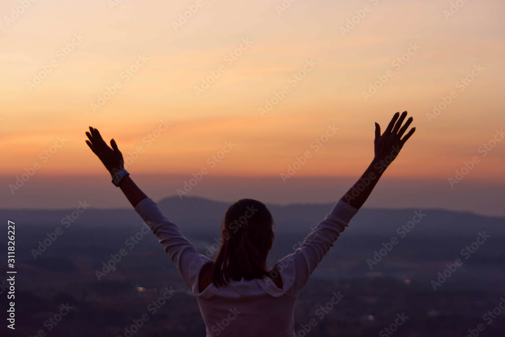 The black silhouette of behind the women raise their arms Background sky orange light of sunset. The black silhouette of behind the women raise their arms Background sky orange light of sunset.