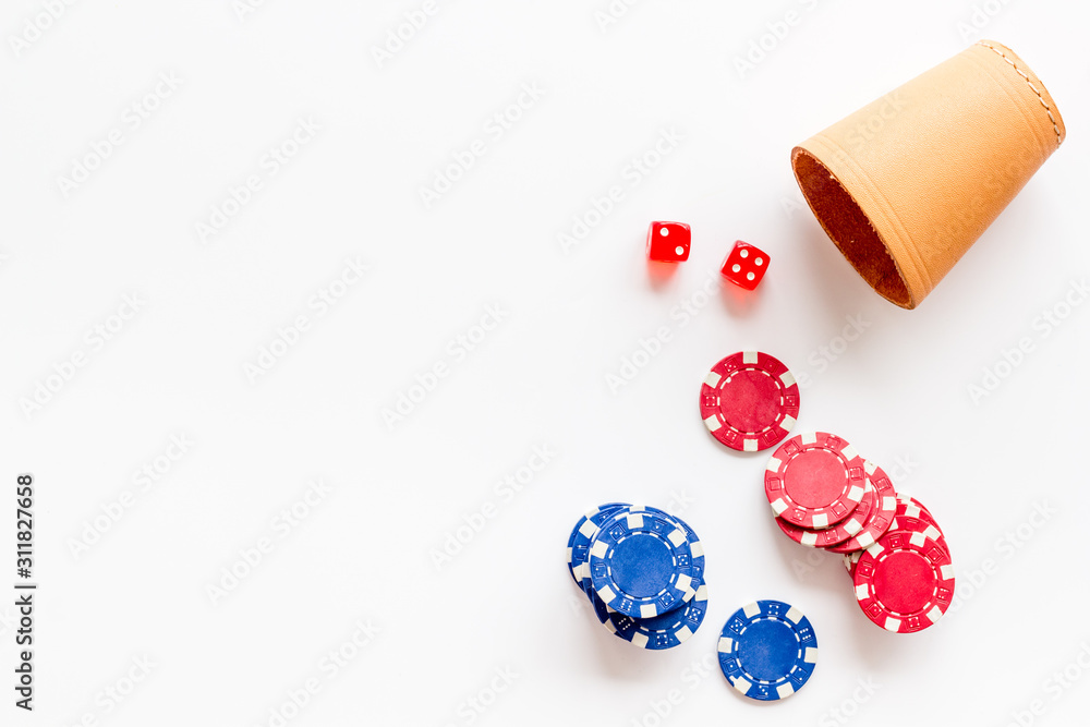Poker concept. Chips, dices, cup for dice on white background top-down copy space Poker concept. Chips, dices, cup for dice on white background top-down copy space