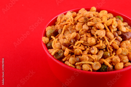 Indian Snacks : Mixture (roasted nuts with salt pepper masala, pulses, channa masala dal, green peas) in red bowl on red background photo