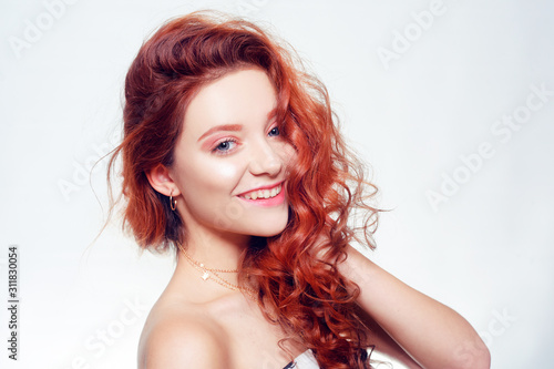 Portrait of a beautiful red-haired girl with gorgeous curls. Redhead. Beauty portrait. Hair care, beautiful skin, white smile.