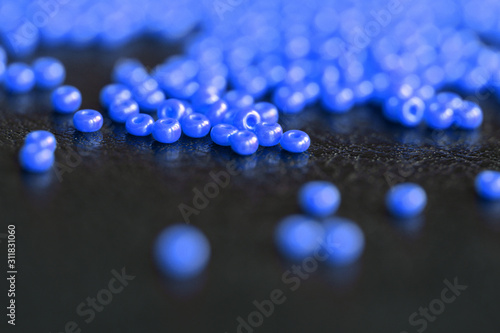 Seed beads blue color scattered on a dark background close up. Handmade and handwork concept
