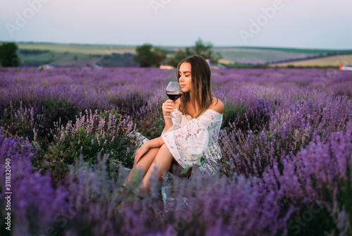 A girl enjoys a glass of wine in a lavender field