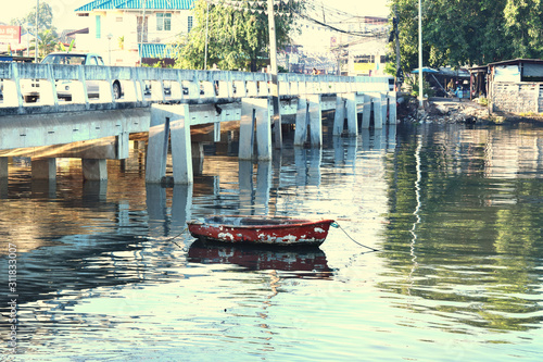 The image of an old small boat floating on a river under the cement bridge. In Chonburi, Thailand