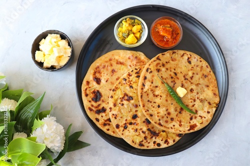Indian Food - Aloo Paratha or Indian Potato stuffed Flatbread. Served with butter for breakfast, pickle and masala potatoes among with Indian Tea or masala chai.  with copy space.