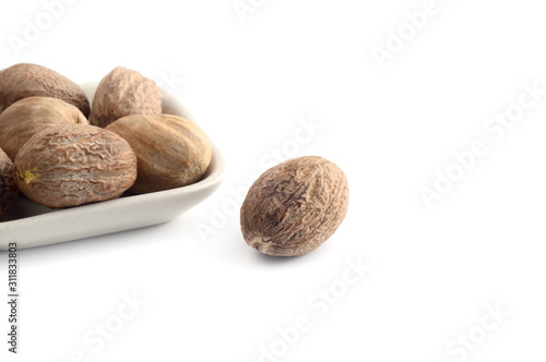 Nutmeg in white plate isolated on white background photo