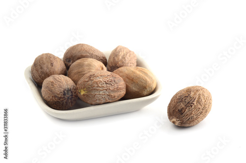 Nutmeg in white plate isolated on white background photo