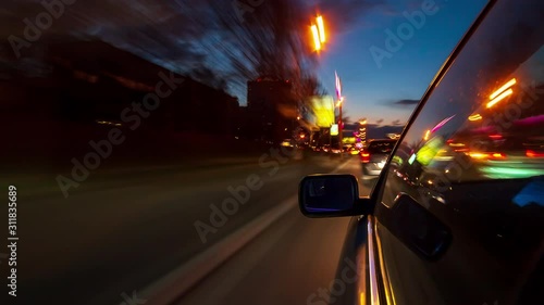Drivelapse urban look from fast driving car at a night avenue in a city timelapse hyperlapse, road with lights reflected on car at high speed. Rapid rhythm of a modern city.