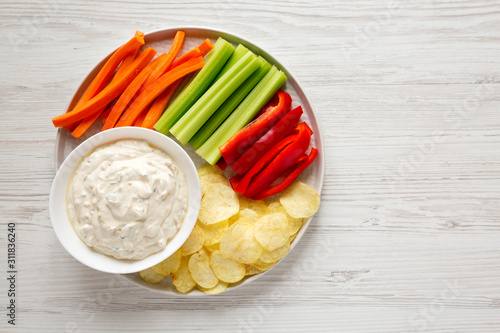 Homemade Caramelized Onion Dip with Potato Chips, Celery, Pepper and Carrot on a white wooden background, top view. Flat lay, overhead, from above. Copy space.