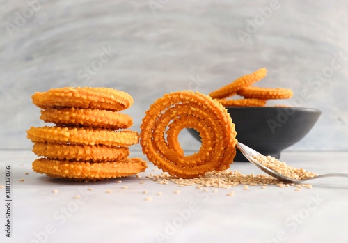 Crunchy fried homemade Chakli in a bowl with sesame seeds. Chakli is a savory snack from India made out of rice, mixed yellow and green lentils along with spices. Mostly eaten during Diwali festival