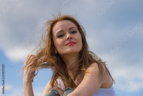 Gorgeous romantic girl outdoors. Brown long hair blowing in the wind against sky. © Voyagerix