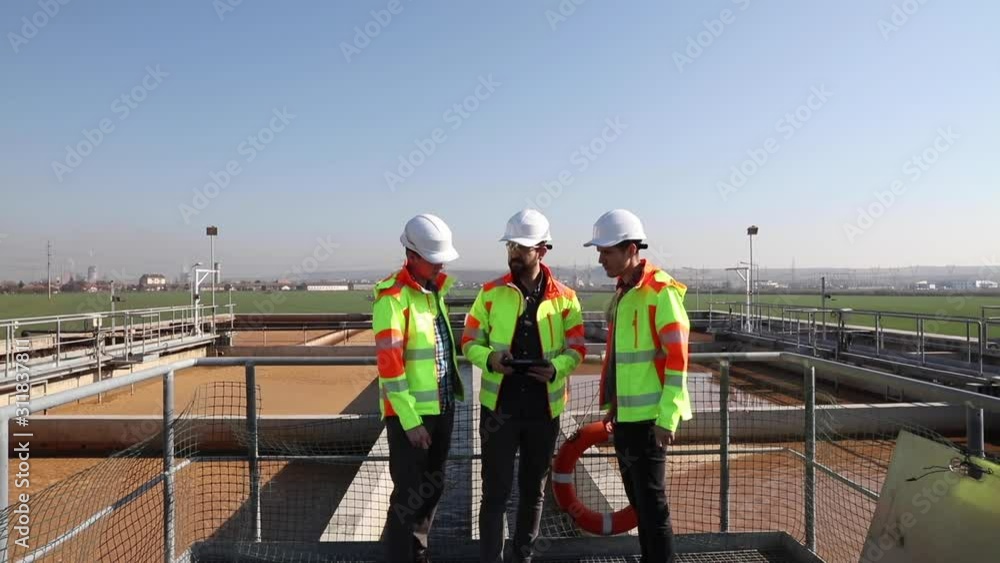 Engineers working on water treatment plant with laptop and measuring sensors Engineers working on water treatment plant with laptop and measuring sensors