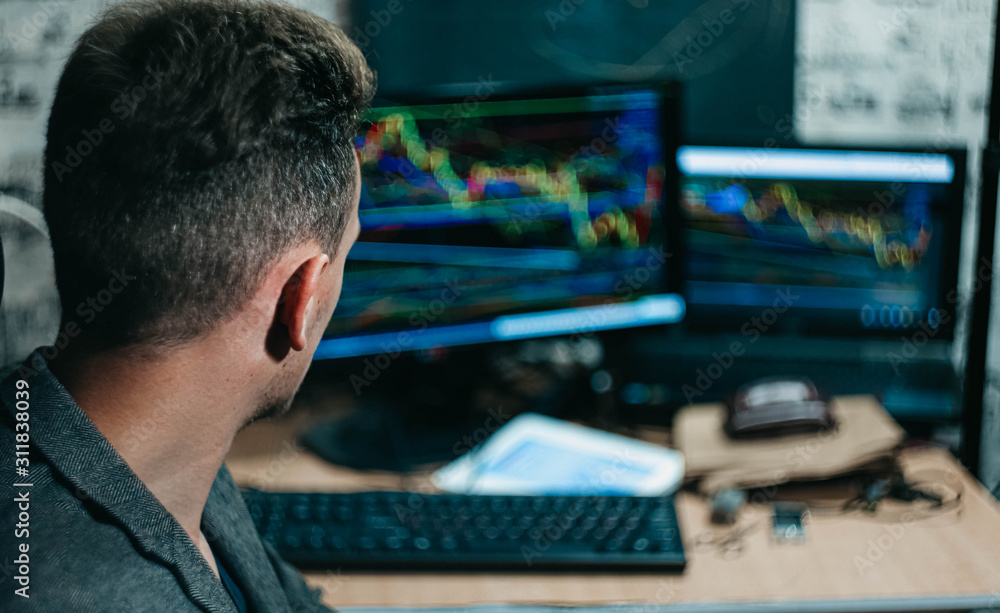 young Slavic male hacker at a computer with a stock exchange and charts. young Slavic male hacker at a computer with a stock exchange and charts.