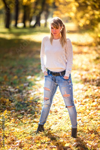 Outdoor close up portrait beautiful blonde girl relax on the ground in the autumn forest in sunny warm day