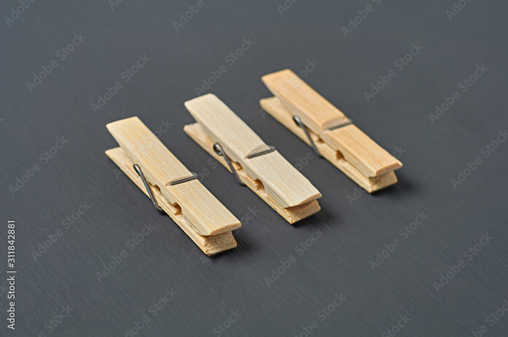 Row of three wooden clothespins lies on dark concrete desk in bathroom. Close-up