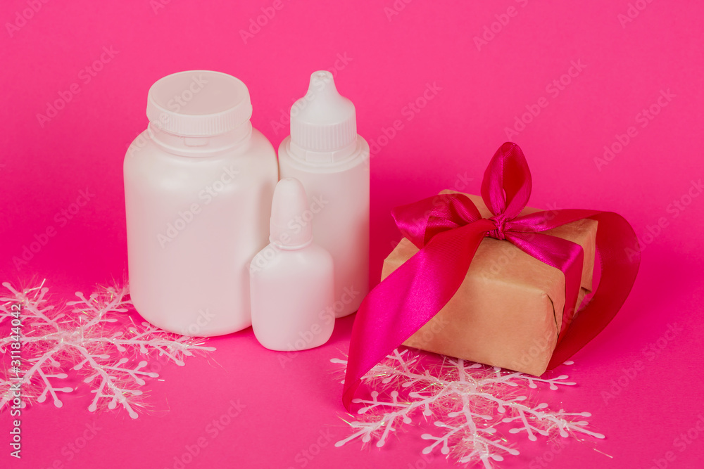 Cosmetics and gift with a pink ribbon. White bottles on a pink background. Cosmetic set on a pink background. Cosmetics and gift with a pink ribbon. White bottles on a pink background. Cosmetic set on a pink background.